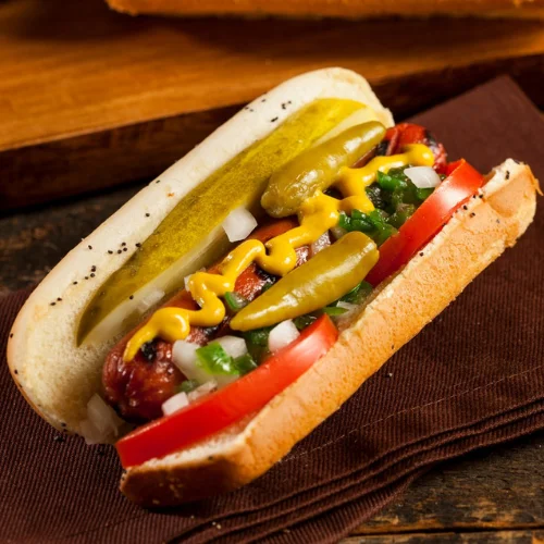 Midway Dog - Our signature Chicago-style hot dog loaded with yellow mustard, neon relish, onion, tomato, sport pepper, pickle spear, and celery salt — never ketchup.